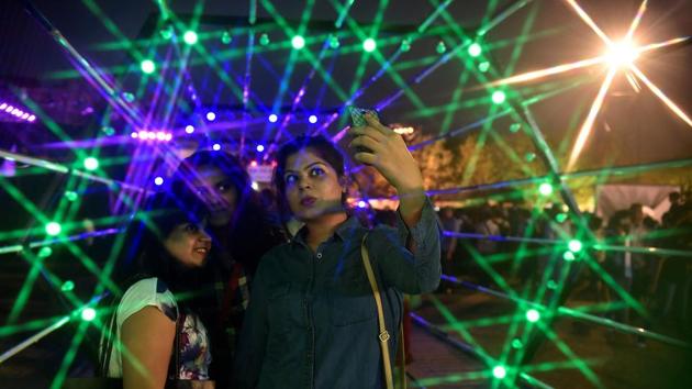 People enjoy an artwork of light at the festival on Sunday. (Anshuman Poyrekar/HT PHOTO) 
