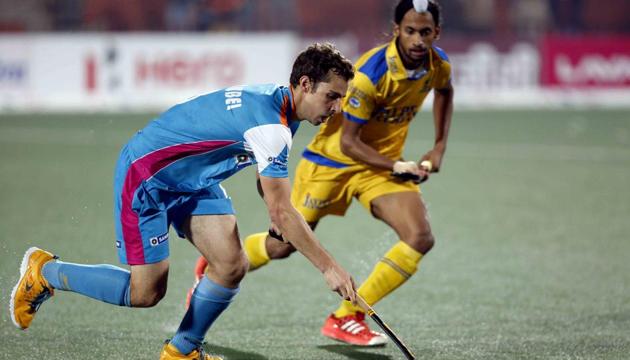 An Uttar Pradesh Wizards player (in blue) tries to dribble past a Jaypee Punjab Warriors player in the Hockey India League match in Chandigarh on Monday.(HIL Photo)