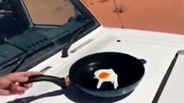 The video posted on the Queensland Police Service’s Facebook page shows an officer from the town of Birdsville cooking an egg with a frying pan on the hood of his vehicle.(Video screengrab)
