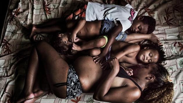 Contemporary Issue, third prize: Edilane and three of her seven children (at the time the photo was taken) rest on a mattress on the floor. She will soon give birth to a son. Despite all her problems and struggles on how to feed her kids, she is still positive about her life. Recently she was able to build up a very small and basic Internet store inside the buildings. Out of approximately 10 old computers, she can make one for the store. (Peter Bauza )