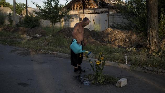 Long Term project, first prize: A man waters flowers on a street in the destroyed village of Spartak, Ukraine. (Valery Melnikov)