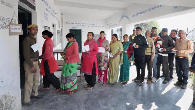 Women voters show voter ID cards as they stand in queue to cast their votes at a polling booth in Raipur constituency in Dehradun on Wednesday.(PTI Photo)
