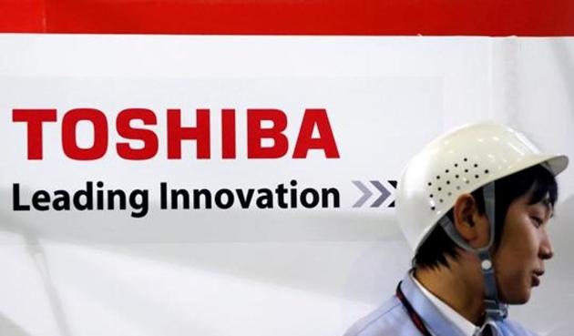 An employee stands next to a logo of Toshiba Corp in Yokohama, south of Tokyo.(REUTERS)