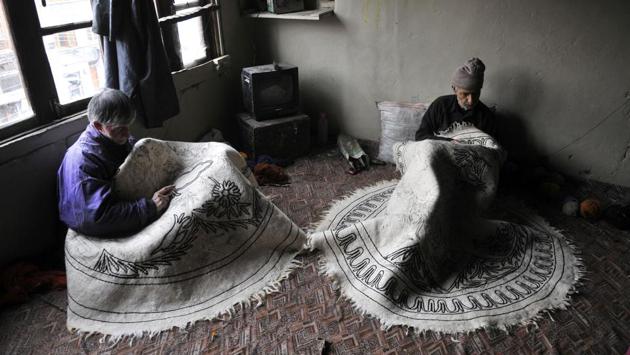 Kashmiri artists doing hand embroidery ‘Aari Kaam’ using colorful dyed threads and the ‘aari’ on a Namda . (Waseem Andrabi /HT PHOTO )