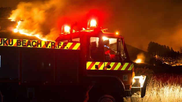 Firefighters combat the wildfires along Worsleys Road in Christchurch before sunrise on February 16, 2017. 200 firefighters were operating about 45 pumps and tankers on the ground, with police and the military also providing additional personnel for the emergency response. (Oliver WATSON / AFP)