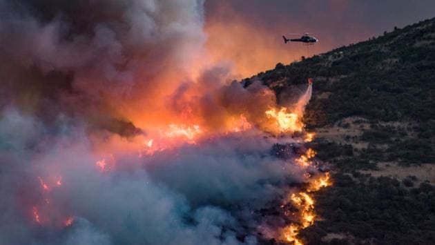 A helicopter dumps fire retardant on wildfires near Christchurch in New Zealand. Fourteen helicopters and three planes were helping battle the blaze, the maximum number of aircraft that could safely operate around the fire-front at one time. (Mark Hannah / REUTERS)