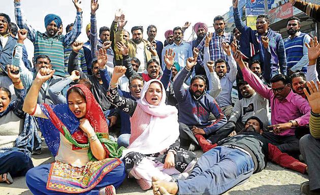 Members of the Punjabi University Employees Union blocking the national highway in front of the university in Patiala on Friday.(HT Photo)