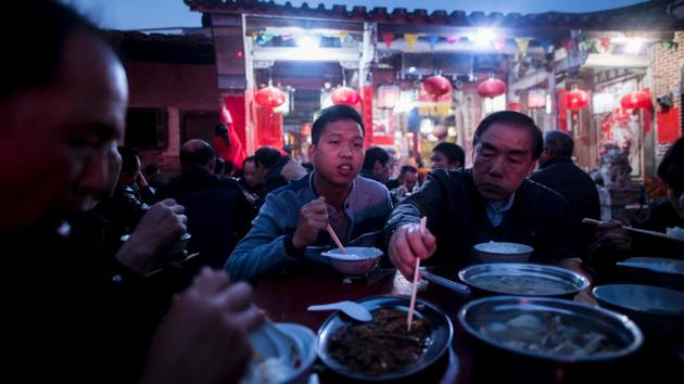 Zheng Yinquan (C) having dinner in front of the temple before performing the 'eating flowers' ritual. (Johannes EISELE / AFP)