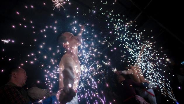 The ‘eating flowers’ ritual involves leaning bare chested into fireworks that spit out white sparks. (Johannes EISELE / AFP)