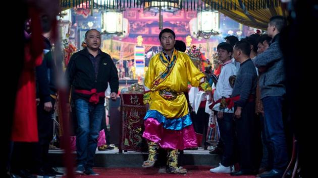 Villager getting ready to perform the 'eating flowers' ritual. The ceremony in the village of Fangshan begins when eight local men selected by village elders don ancient-style Chinese dress to pray in a temple for protection from the Buddha. (Johannes EISELE / AFP)