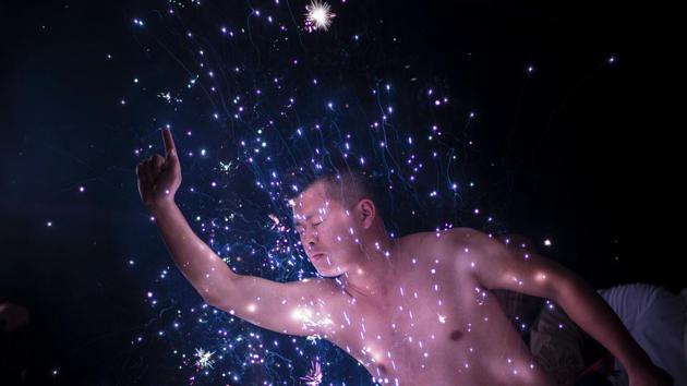 With eyes closed, they lean their faces into fireworks that spit out white sparks, which has given the ceremony its local name, “eating flowers”. (Johannes EISELE / AFP)