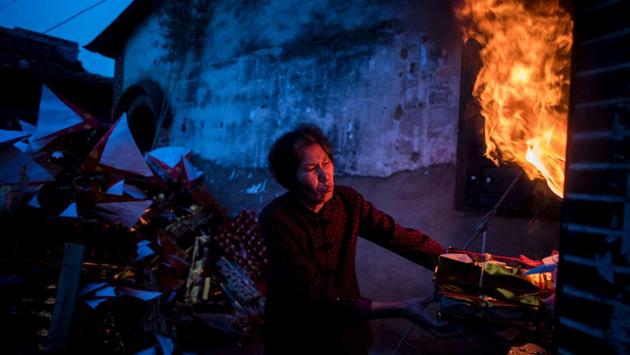 A villager burning incense and paper money before the start of the 'eating flowers' ritual. (Johannes EISELE / AFP)