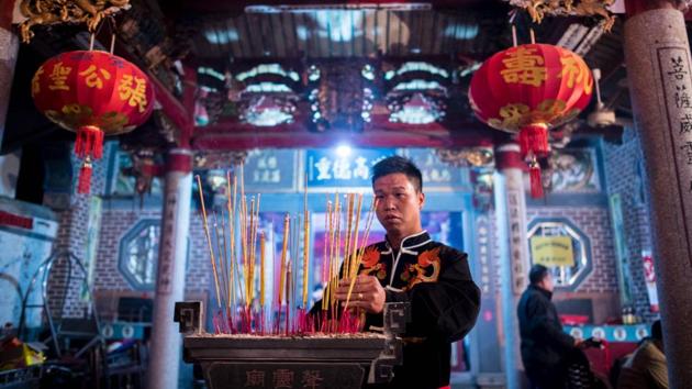 Zheng Yinquan burning incense before performing the 'eating flowers' ritual. (Johannes EISELE / AFP)