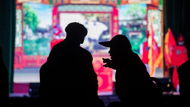 Two villagers having a chat in front of a stage before the start of the 'eating flowers' ritual. (Johannes EISELE / AFP)