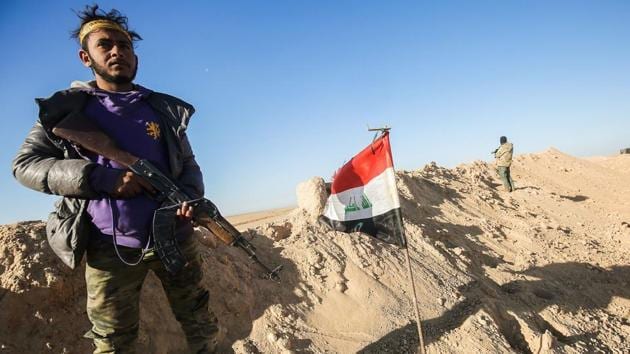 A fighter of the Hashed al-Shaabi (Popular Mobilisation) paramilitaries poses for a picture carrying a Kalashnikov assault rifle next to an Iraqi flag at a defensive position near the frontline village of Ayn al-Hisan, on the outskirts of Tal Afar west of Mosul.(AFP Photo)
