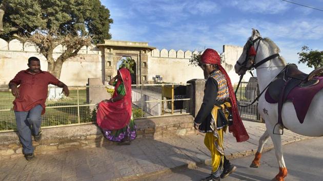 Locals and tour guides wait for tourists to pose for pictures outside Rani Padamawati's mahal at the fort complex. (Raj K Raj/HT PHOTO)