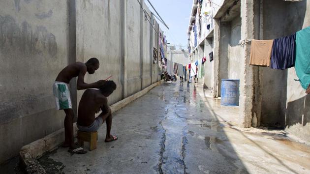 A prisoner combs the hair of a fellow inmate during recreation time. (Dieu Nalio Chery/AP)