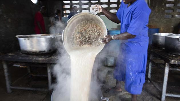 A prisoner pours hot oatmeal into a a large stock pot in the kitchen of the National Penitentiary. Some inmates are provided meals by visiting relatives but the majority of prisoners are dependent on authorities to feed them twice a day and get little more than rationed supplies of rice, oats or cornmeal. (Dieu Nalio Chery/AP)