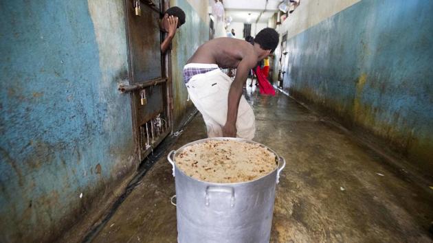 A prisoner pulls a large stock pot filled with rice and beans during lunch. Prison authorities say they try their best to meet inmates' needs, but repeatedly receive insufficient funds from the state to buy food and cooking fuel, leading to deadly cases of malnutrition-related ailments such as beriberi and anemia. (Dieu Nalio Chery/AP)