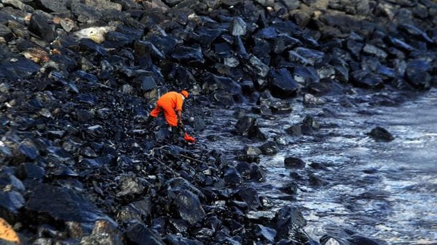A member of the Pollution Response Team collects a sample of an oil spill from boulders at the coast, a day after an oil tanker and an LPG tanker collided off Kamarajar Port in Ennore, in Chennai on January 30, 2017.(AFP Photo)