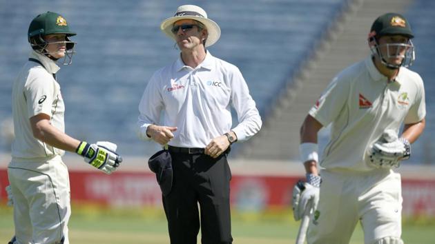 Australia captain Steve Smith (left) and umpire Nigel Llong of England look on as Matthew Renshaw holds his stomach while running back to the pavilion on Day 1 of the first Test against India in Pune on Thursday.(AFP)