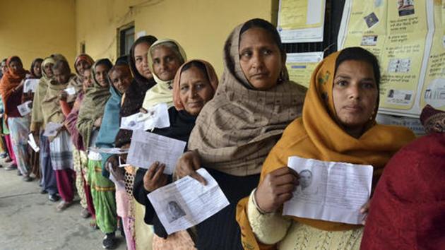 Women display their election identity cards as they stand in a queue to cast their votes outside a polling station, Chogawan, near Amritsar, Punjab, February 4.(AP)