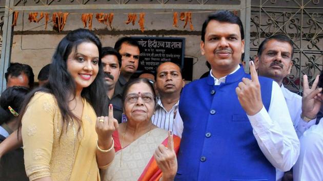 Maharashtra chief minister Devendra Fadnavis with his mother (C) and wife after casting his vote for the municipal election in Nagpur on Tuesday.(PTI)