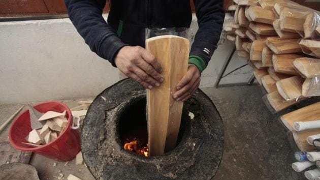 A worker laminates a bat by dipping it into a furnace. (Waseem Andrabi / HT Photo)