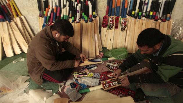 Pasting stickers on the now nearly finished cricket bats. (Waseem Andrabi / HT Photo)