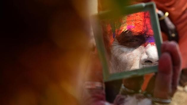 A Hindu sadhu smears coloured paste onto his face at the Pashupatinath Temple . (PRAKASH MATHEMA / AFP) A Hindu sadhu smears coloured paste onto his face at the Pashupatinath Temple . (PRAKASH MATHEMA / AFP)