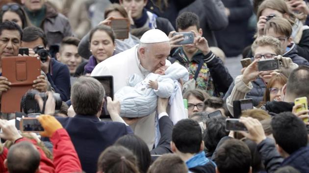 Pope Francis kisses a baby as he is driven through the crowd during his weekly general audience at St. Peter's Square in the Vatican on Wednesday.(AP)