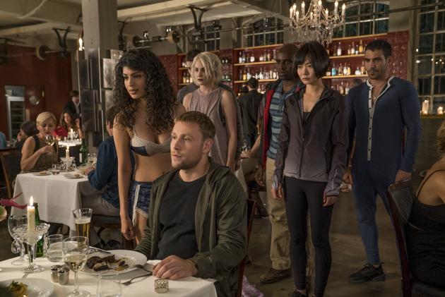 Six Sensates join in for Wofgang’s dinner (don’t miss Will in the background). The expressions suggest the mafia might be seated opposite him. (Jane Ackroyd/netflix; text: sarit ray)