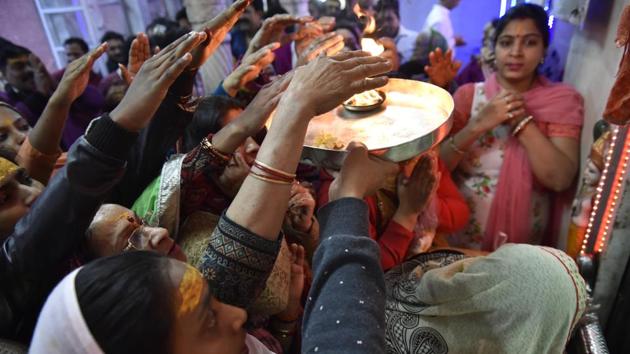 A lady holds up a thali with a burning flame to bless devotees. (Saumya Khandelwal/HT PHOTO)