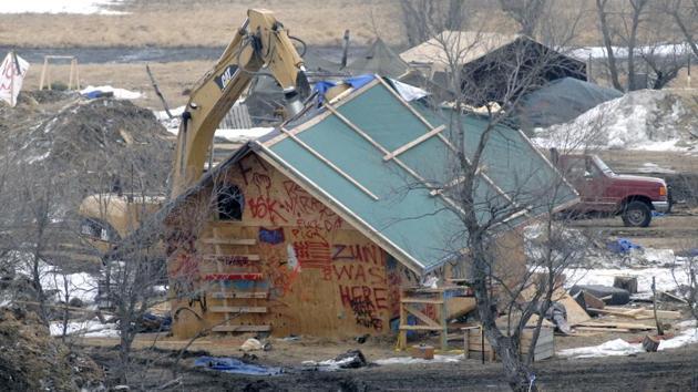 A backhoe rips through a wood structure to begin the cleaning up process at the Oceti Sakowin camp as law enforcement swept through the camp arresting the final Dakota Access oil pipeline protesters in Morton County. (Mike McCleary/The Bismarck Tribune via AP)