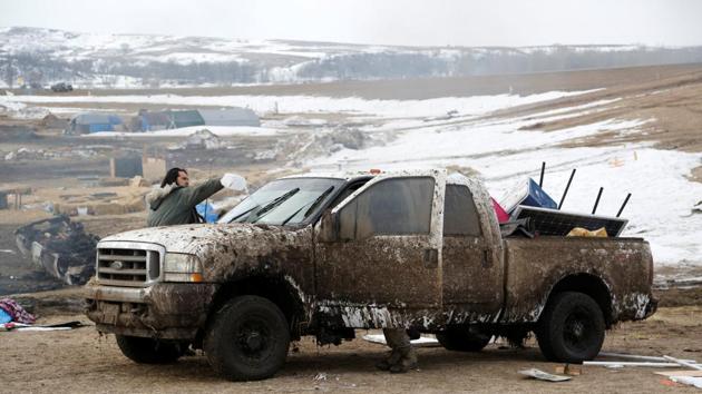 A protester washes mud from his truck before evacuating. As police in full riot gear worked to arrest the stragglers Thursday, cleanup crews began razing buildings on the square-mile piece of property at the confluence of the Cannonball and Missouri rivers. (Terray Sylvester/REUTERS)