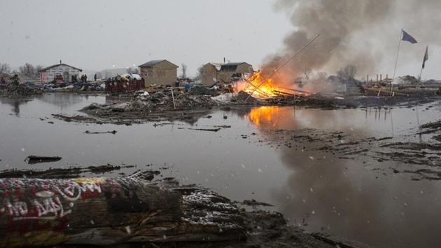 Protesters watch as structures are burned at the Oceti Sakowin protest camp before a 2 p.m. deadline to vacate in Cannon Ball. A dwindling band of activists protesting the Dakota Access oil pipeline remained camped along the banks of the Missouri River as a Wednesday afternoon deadline for them to leave had passed. (Nick Cote/NYT)