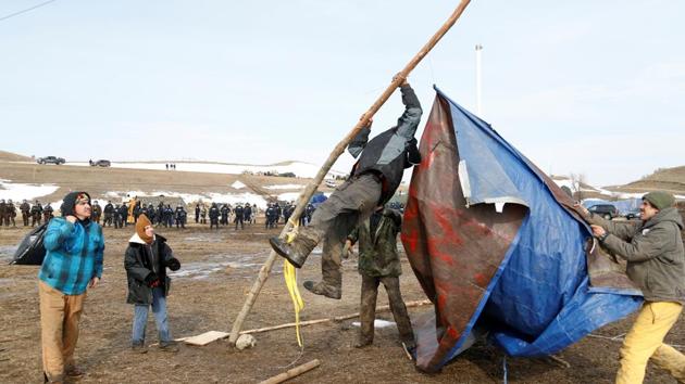 Protesters salvage a banner as law enforcement officers advance into the main opposition camp. (Terray Sylvester/REUTERS)