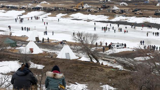 Protesters watch law enforcement officers guard the edge of the main opposition camp. (Terray Sylvester/REUTERS)
