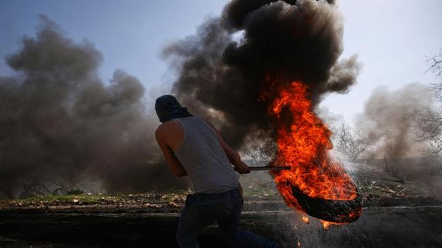 A Palestinian protester moves a burning tyre during clashes with Israeli troops following a protest against the nearby Jewish settlement of Qadomem, in the West Bank village of Kofr Qadom near Nablus. (Mohamad Torokman/REUTERS) A Palestinian protester moves a burning tyre during clashes with Israeli troops following a protest against the nearby Jewish settlement of Qadomem, in the West Bank village of Kofr Qadom near Nablus. (Mohamad Torokman/REUTERS)