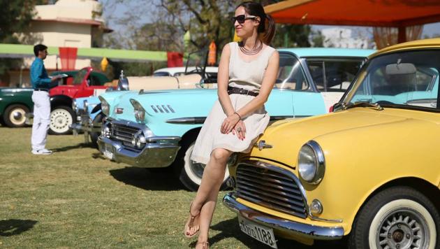A visitor poses for a photograph in front of a vintage car at the 19th Vintage & Classic Car Rally in Jaipur. The three day exhibition and rally consists of around 100 vintage and classic cars from over the country. (Himanshu Vyas/ HT Photo)