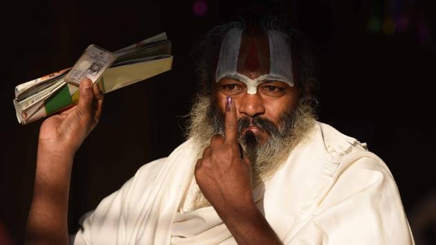 A sadhu shows his inked finger after casting his vote at a polling booth during the fifth phase of UP assembly election in Ayodhya on Monday.(Arun Sharma/HT PHOTO)