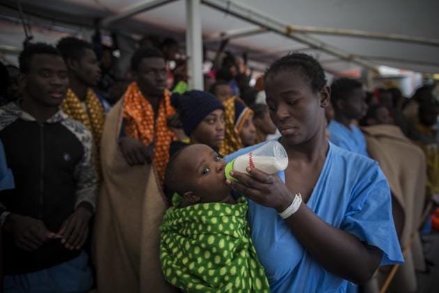 A woman from Ivory Coast feeds her baby aboard the Golfo Azurro, the Spanish NGO Proactiva Open Arms rescue ship, as she waits with other refugees and migrants, to disembark at the Italian port of Reggio Calabria. (Santi Palacios / AP)