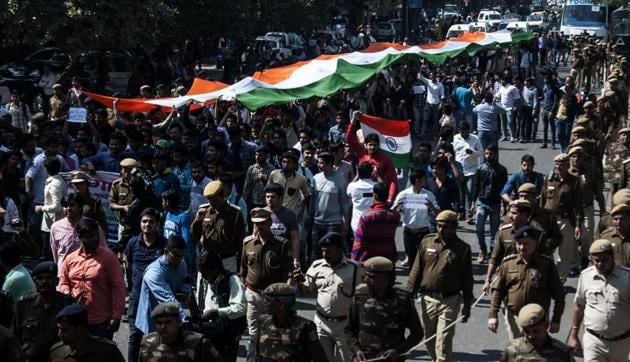 Students of the Akhil Bharatiya Vidyarthi Parishad (ABVP) are watched by security personnel as they shout slogans while carrying a giant Indian tricolour during a 'Tiranga March' on the campus of Delhi University in New Delhi on Monday.(AFP)