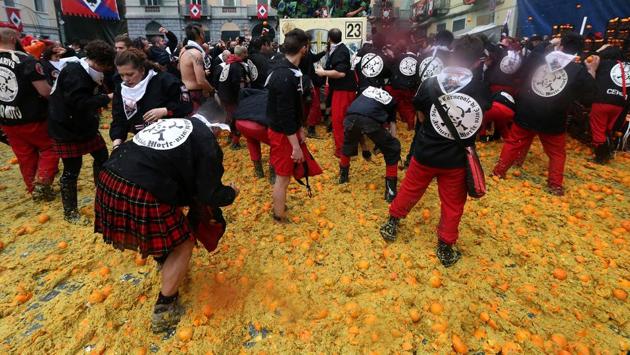 Crates of oranges are tightly stacked one over the other stand on the sidewalks, and some spectators take refuge to avoid being hit by wayward pulp. (Stefano Rellandini / REUTERS)
