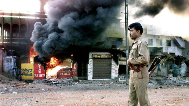In this picture taken 01 March 2002, an Indian policeman looks on as a row of shops burns in Ahmedabad. (AFP)