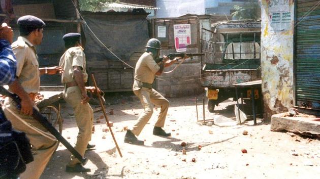 A policeman (C) shoots on an angry mob at Millat Nagar in Ahmedabad on March 01, 2002 . (AFP FILE PHOTO)