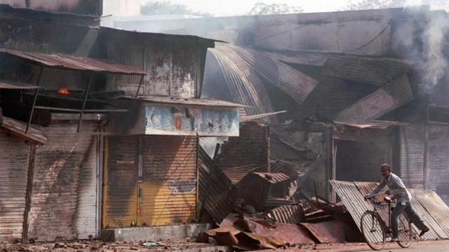 A man rides a bicycle in the deserted streets of Ahmedabad near Dilli Darwaza.Tens of thousands of homes and small business establishments — petty shops, wooden carts, autorickshaws, taxi jeeps, eateries and garages — were set aflame. (KAUSHIK RAMASWAMY / HT FILE PHOTO)