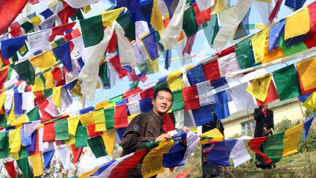 A Tibetan man ties prayer flags on a string during the ‘Losar’, or Tibetan New Year celebrations.. A Tibetan man ties prayer flags on a string during the ‘Losar’, or Tibetan New Year celebrations..