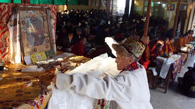 A Tibetan old man offering traditional white Khata (traditional Tibetan scarf) in front of Dalai Lama picture during special Morning Prayer session on the third and one of the most important day of the ‘Losar’. A Tibetan old man offering traditional white Khata (traditional Tibetan scarf) in front of Dalai Lama picture during special Morning Prayer session on the third and one of the most important day of the ‘Losar’.
