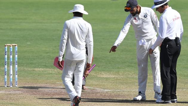 Virat Kohli pointing out marks on the pitch to on-field umpire Richard Kettleborough of New Zealand as Ravindra Jadeja looks on during third day’s play of the first Test against Australia at the Maharashtra Cricket Association Stadium in Pune. Match referee Chris Broad has rated the Pune track as poor after the match finished in less than three days and India lost by 333 runs.(AFP)